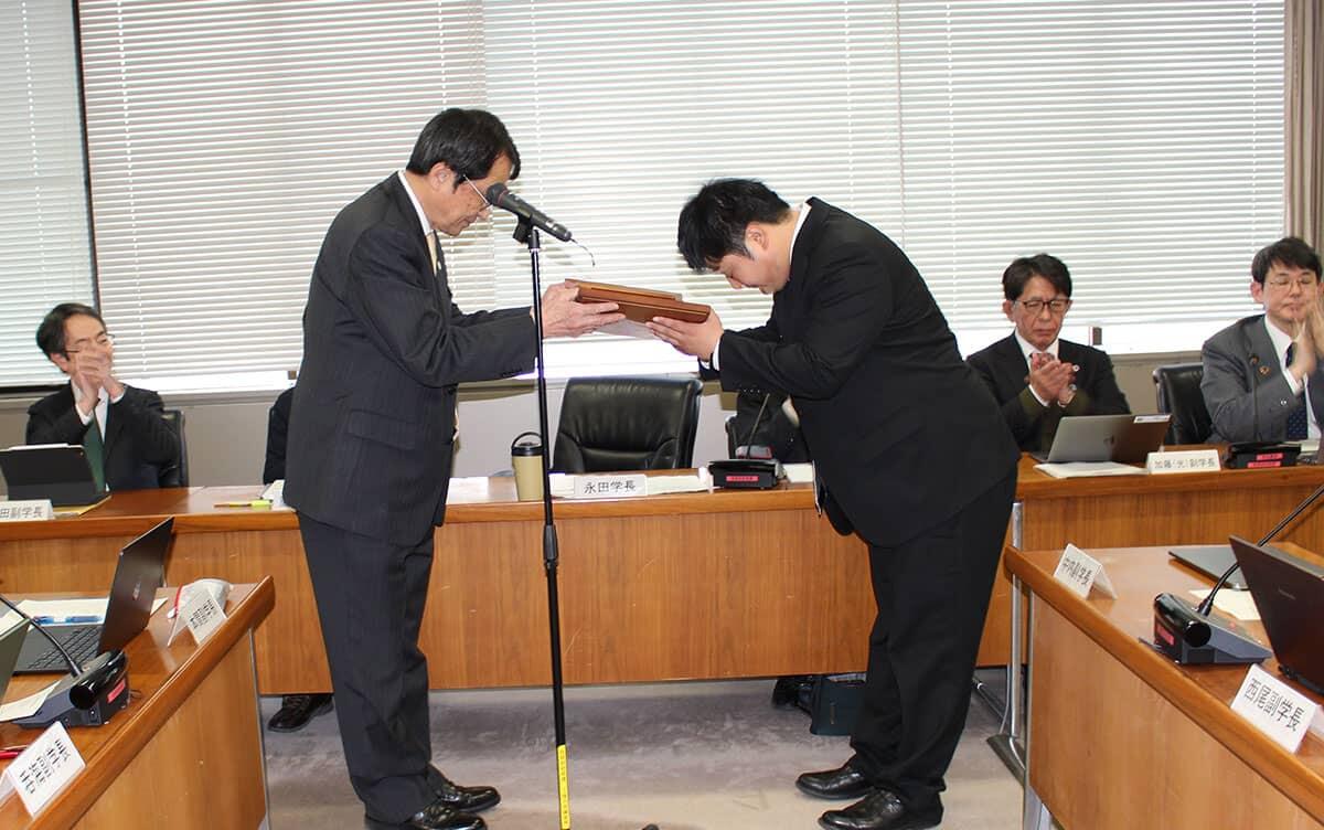 写真:永田学長から表彰楯を授与される宮川准教授
